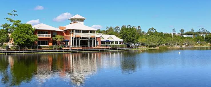 Springfield Lakes community centre building and boardwalk overlooking Spring Lake water reflections